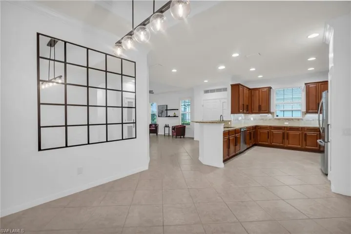 Kitchen featuring light tile patterned flooring, light stone counters, backsplash, kitchen peninsula, and stainless steel appliances