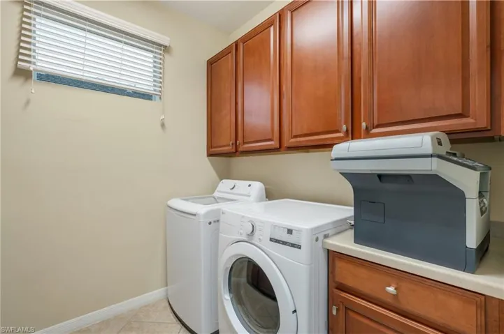 Laundry room featuring cabinets, light tile patterned floors, and washing machine and dryer