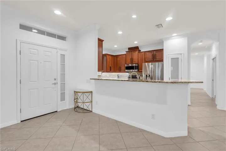 Kitchen featuring light stone counters, appliances with stainless steel finishes, crown molding, and kitchen peninsula