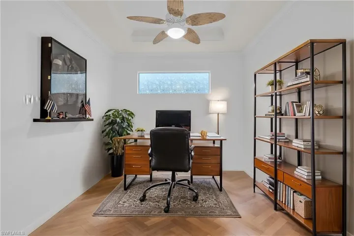 Office area with ornamental molding, light parquet flooring, and ceiling fan