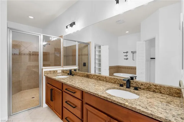 Bathroom with tile patterned flooring, vanity, and separate shower and tub