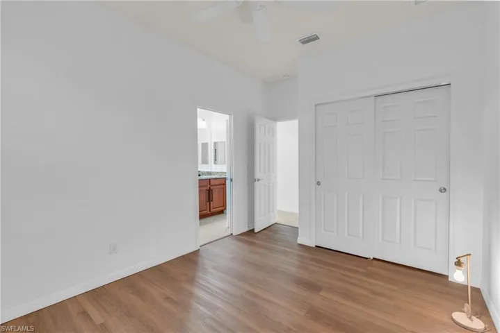 Unfurnished bedroom with ceiling fan, a closet, connected bathroom, and light hardwood / wood-style floors