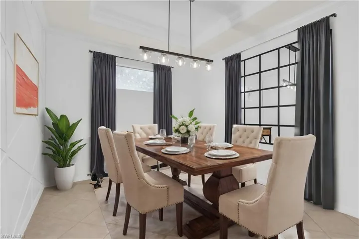 Dining space featuring ornamental molding, a raised ceiling, and light tile patterned floors