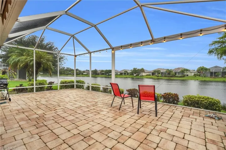 View of patio featuring glass enclosure and a water view