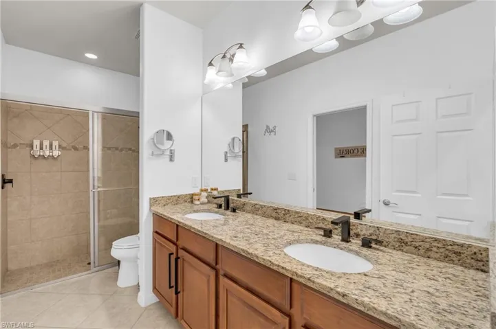 Bathroom featuring tiled shower, vanity, toilet, and tile patterned floors