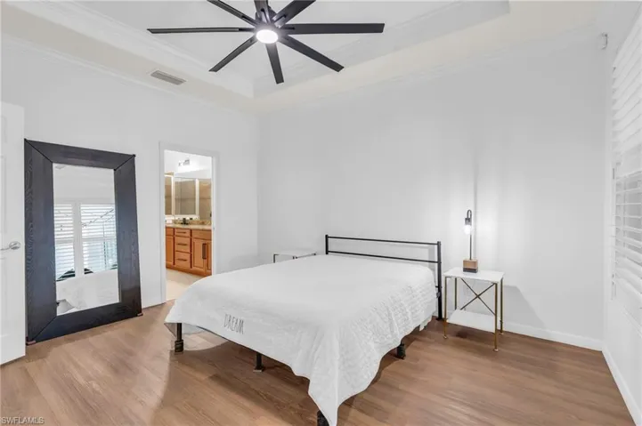 Bedroom featuring ceiling fan, connected bathroom, ornamental molding, and wood-type flooring
