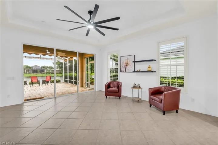 Living area featuring light tile patterned floors, a tray ceiling, ceiling fan, and plenty of natural light