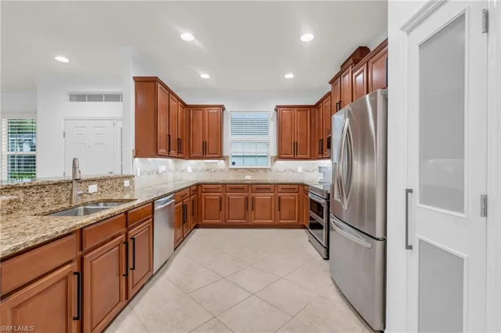 Kitchen featuring light stone countertops, stainless steel appliances, plenty of natural light, and sink