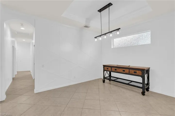 Dining room with a tray ceiling, light tile patterned flooring, and crown molding