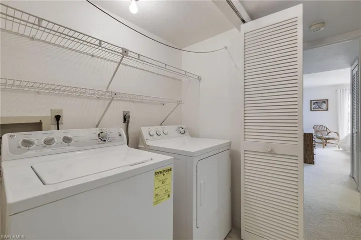 Clothes washing area featuring light carpet, independent washer and dryer, and hookup for an electric dryer