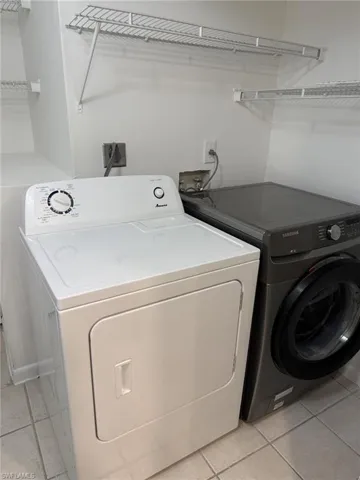 Washroom with washer and clothes dryer and light tile patterned floors