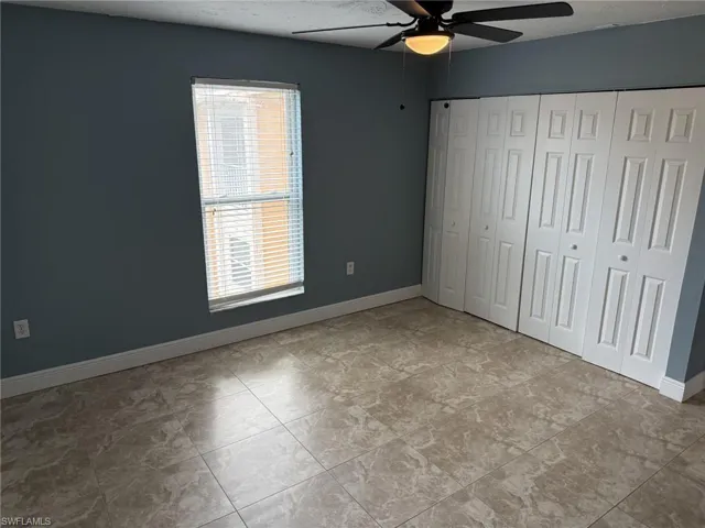 Unfurnished bedroom featuring multiple windows, a closet, and ceiling fan