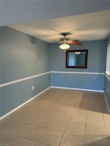 Tiled empty room featuring ceiling fan and a textured ceiling
