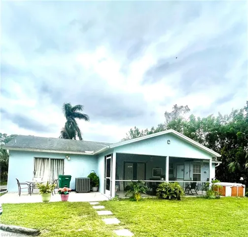 Back of property with a patio area, central AC, a yard, and a sunroom