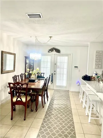Dining area with a notable chandelier, a textured ceiling, and light tile patterned floors