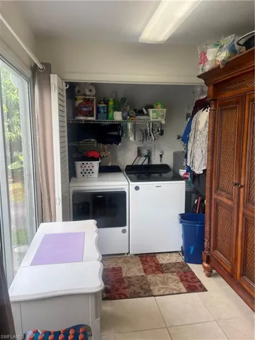 Laundry area with washer and dryer and light tile patterned floors