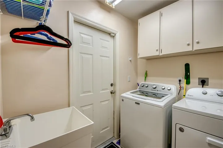 Laundry room featuring sink, washing machine and new clothes dryer, and built in cabinets. Door leads to the double car garage.