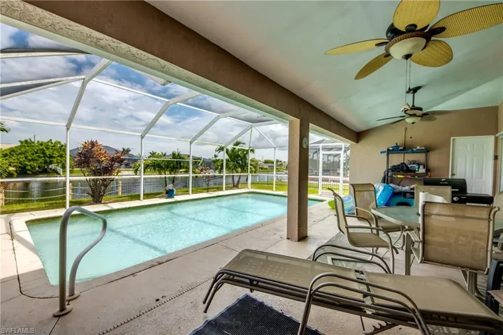 Swimming pool with a lanai, 2 ceiling fans, and a large patio area and view of the canal.