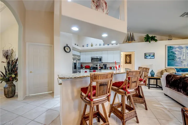 Kitchen with granite counters, a breakfast bar area, white cabinets, appliances with stainless steel finishes, and the same tile floors throughout.