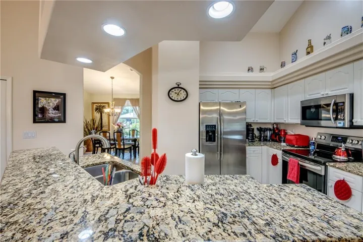 Kitchen featuring a double stainless steel sink, white cabinetry, appliances with stainless steel finishes, and beautiful granite countertops