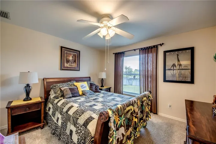 Another guest bedroom Carpeted with ceiling fan and window treatments.