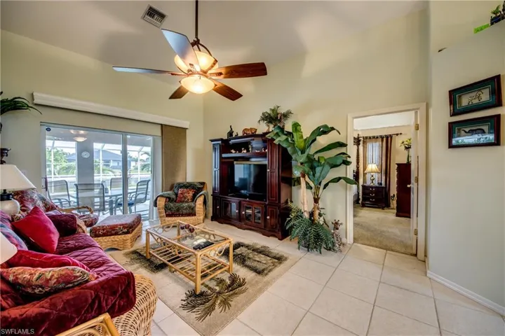 Another view of living room with ceiling fan and lofty ceiling. Door on right to enter primary bedroom.