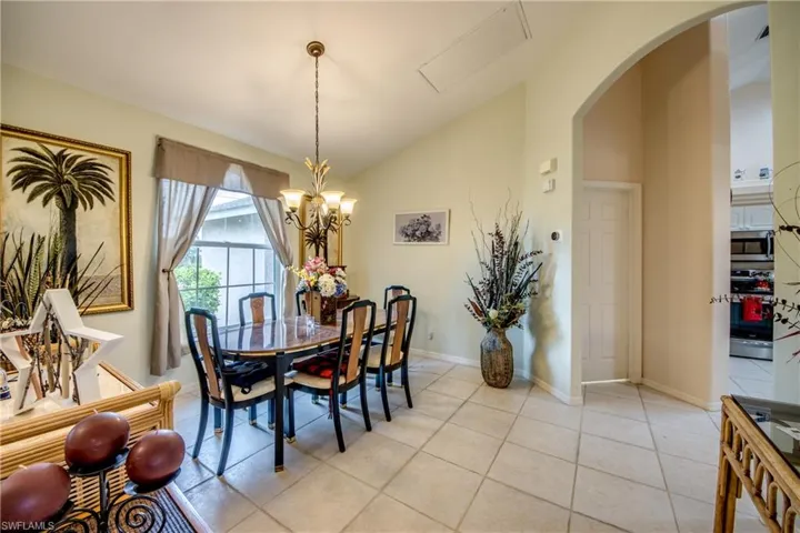 Tiled dining space featuring lofted ceiling and a chandelier