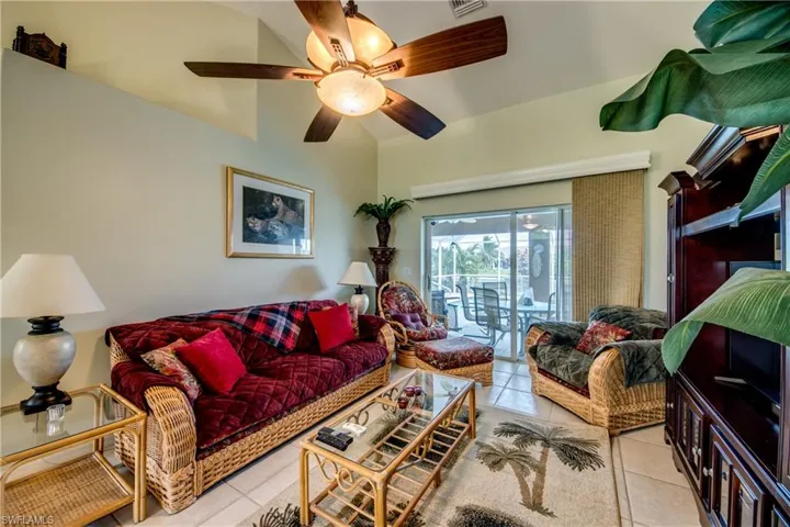 Very comfortable living room featuring ceiling fan, light tile flooring, and vaulted ceiling