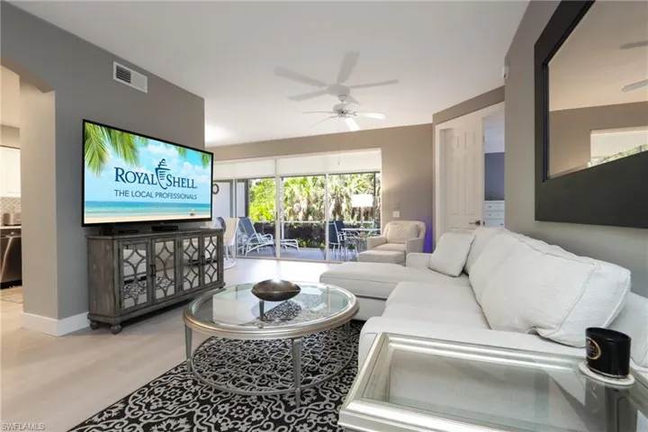 Living area with a ceiling fan, wood finished floors, arched walkways, and baseboards