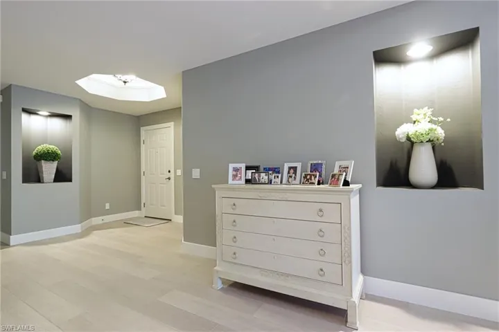 Hall featuring a skylight, baseboards, and light wood finished floors