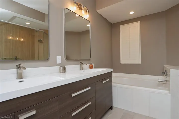 Bathroom featuring a garden tub, double vanity, recessed lighting, and a shower