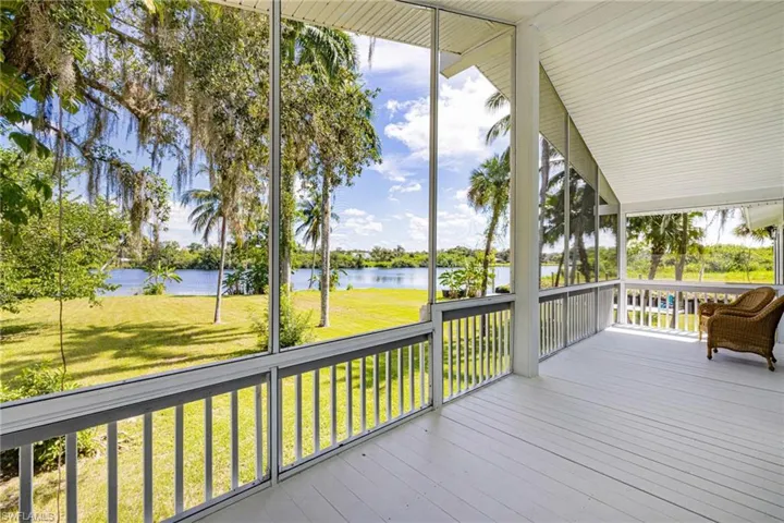 Wooden terrace with a water view, a yard, and a sunroom