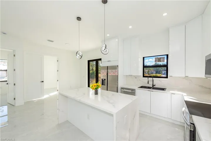 Kitchen featuring modern cabinets, white cabinets, a center island, stainless steel appliances, and recessed lighting