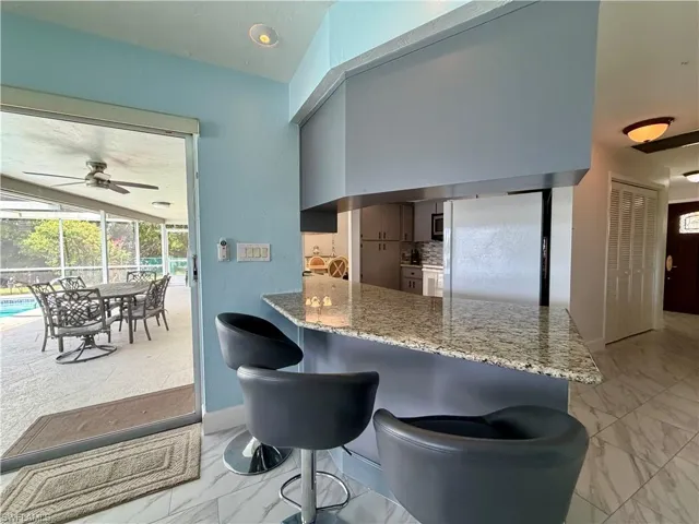Kitchen bar area featuring a granite countertop and contemporary pendant lighting