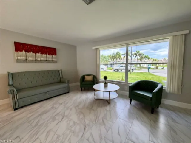 Spacious living area featuring large windows, light gray walls, and white baseboards