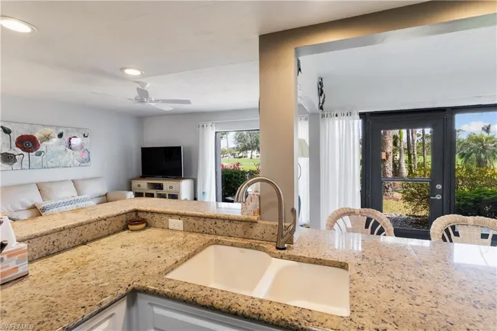 Kitchen featuring light stone countertops, ceiling fan, and sink