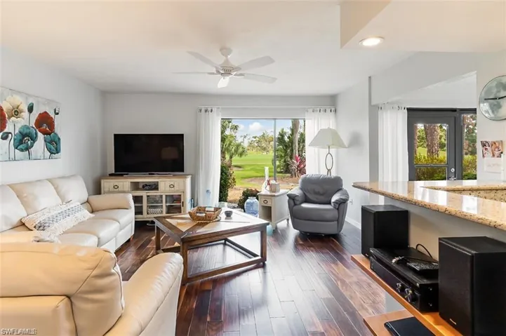 Living room with ceiling fan, a healthy amount of sunlight, and dark hardwood / wood-style flooring