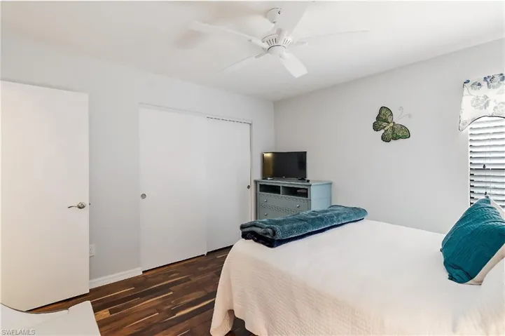 Bedroom with ceiling fan, dark hardwood / wood-style flooring, and a closet