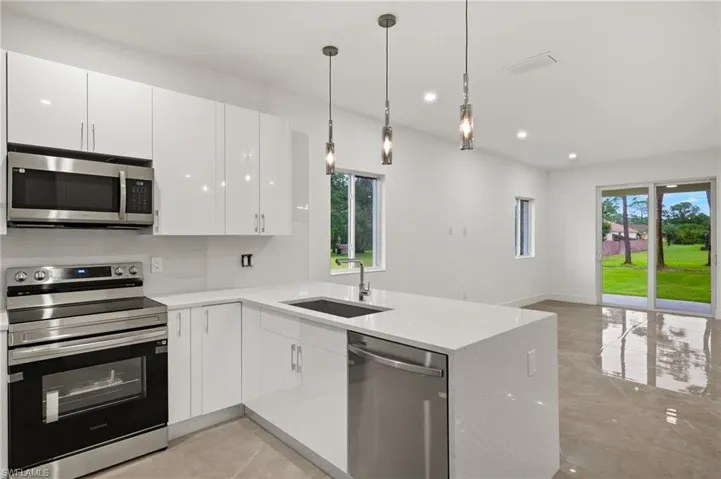 Kitchen featuring kitchen peninsula, sink, stainless steel appliances, and white cabinets