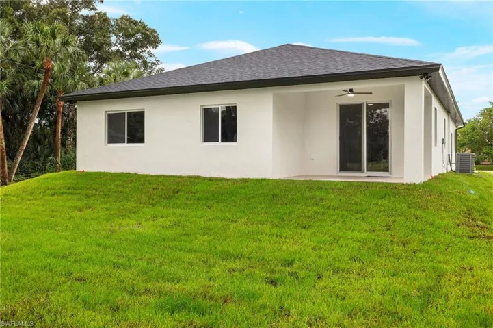 Back of house with ceiling fan, a yard, a patio area, and central AC unit