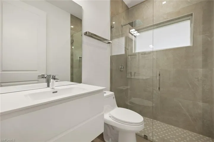 Bathroom featuring vanity, a shower with door, and toilet