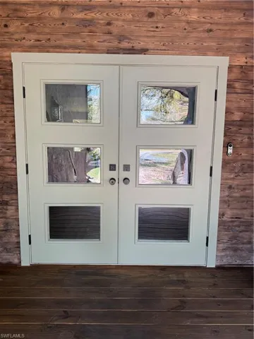 Detailed view of french doors, wood finished floors, and wood walls