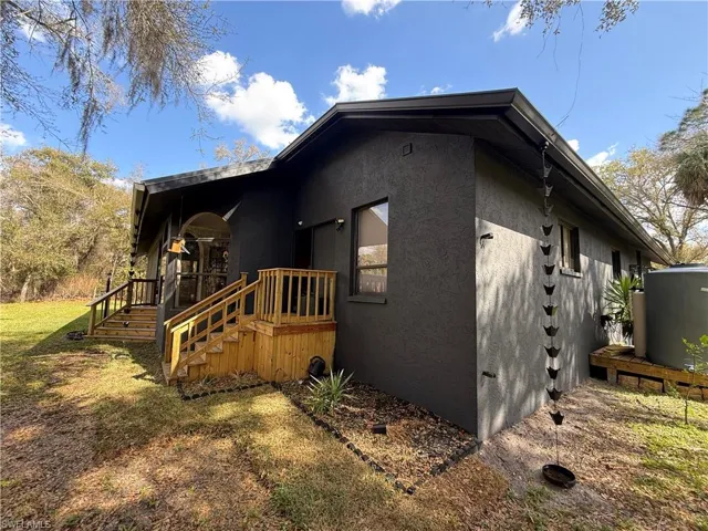 View of side of home featuring stucco siding, a deck, and a yard