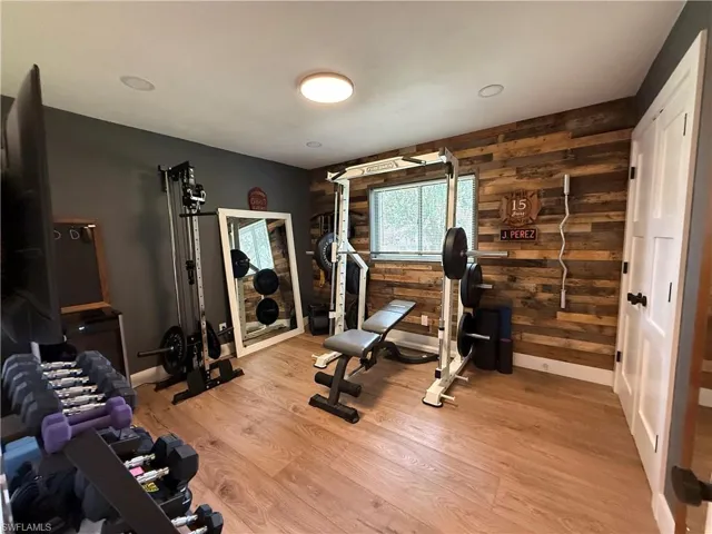 Workout room featuring wood walls and light wood-style flooring