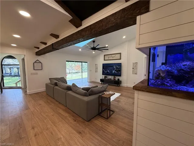 Living area with light wood-style flooring, vaulted ceiling with beams, recessed lighting, and a ceiling fan