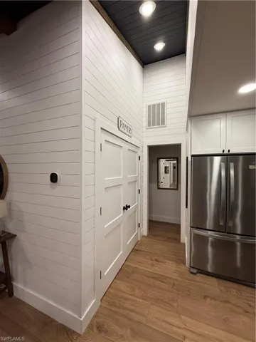 Hallway featuring dark wood-style floors, recessed lighting, and wood walls