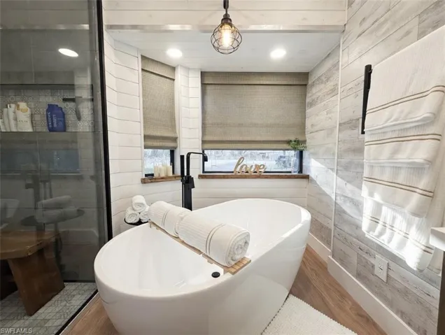 Full bath featuring wood finished floors, a freestanding tub, and recessed lighting