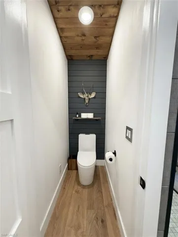 Bathroom with light wood finished floors, wooden ceiling, and wooden walls