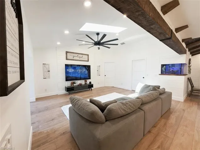 Living area featuring light wood-style floors, a skylight, lofted ceiling, a ceiling fan, and recessed lighting