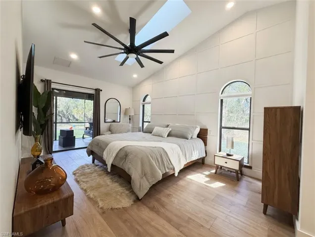 Bedroom with light wood-style floors, vaulted ceiling, access to outside, recessed lighting, and multiple windows